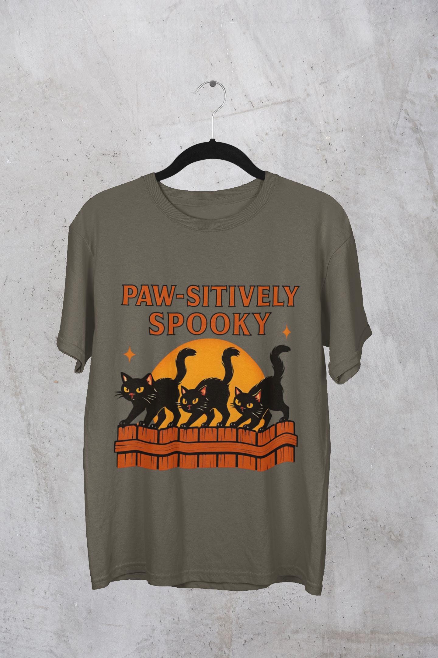 Paw-sitively Spooky Cat Tshirt, Whether you're a devoted cat dad or gifting it to a feline-loving friend, this cute Halloween cat apparel spreads pawsitive vibes with its blend of spooky black cats and cheeky charm.
