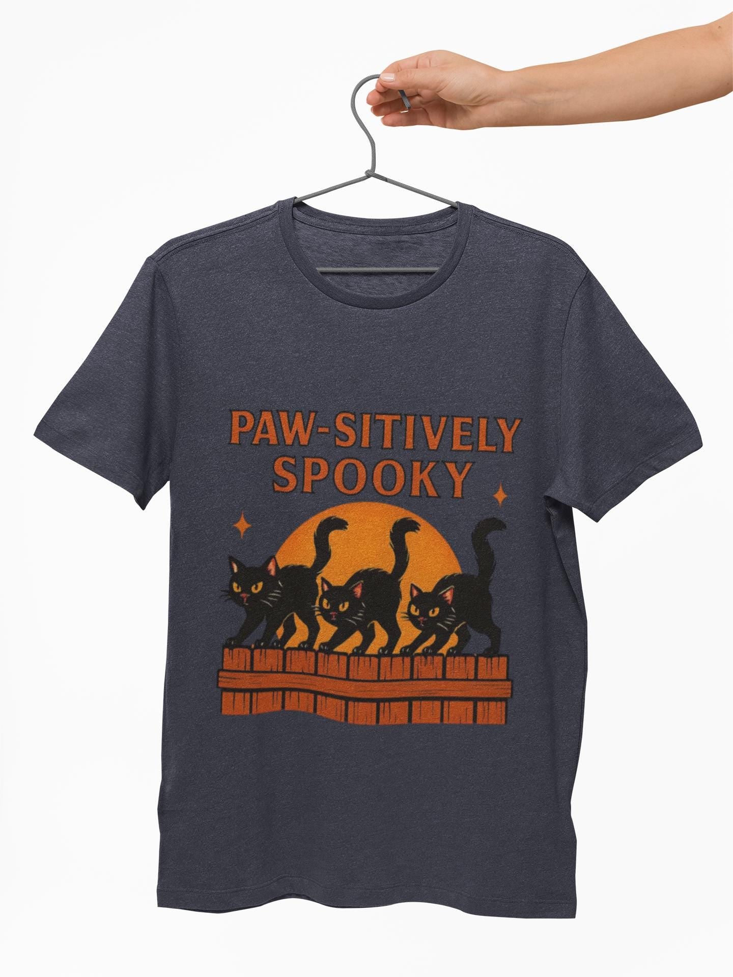 Paw-sitively Spooky Cat Tshirt, Whether you're a devoted cat dad or gifting it to a feline-loving friend, this cute Halloween cat apparel spreads pawsitive vibes with its blend of spooky black cats and cheeky charm.